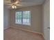 This carpeted bedroom has a ceiling fan and a window with a view of the outside at 1080 Smoke Hill Ln, Hoschton, GA 30548