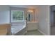 This bathroom boasts a tub with tile surround, vanity with sink, and bright window at 1080 Smoke Hill Ln, Hoschton, GA 30548