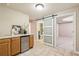 A basement wet bar including a mini fridge, cabinets, and a sliding barn door to the renovated bathroom at 5605 Preserve Cir, Johns Creek, GA 30005