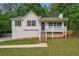 Charming home featuring a cozy front porch, neutral siding, green lawn, and mature trees at 148 White Pine Ln, Temple, GA 30179
