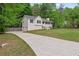 Front view of home with a long driveway, well kept lawn, and mature trees at 148 White Pine Ln, Temple, GA 30179