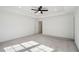 Spacious primary bedroom with a tray ceiling, ceiling fan, gray carpet, and a doorway to the bathroom at 2946 Stockholm Way, Suwanee, GA 30024