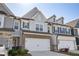Desirable townhome showing off a two-car garage, gray and brick exterior, and manicured lawn at 2946 Stockholm Way, Suwanee, GA 30024