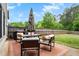 Cozy back patio features an outdoor dining set with an umbrella, plus a grill, all overlooking a grassy yard and wood fence at 135 Haleys Cir, Woodstock, GA 30188