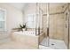 Bright bathroom featuring a soaking tub, separate shower with glass enclosure, and neutral tile surround at 135 Haleys Cir, Woodstock, GA 30188