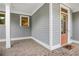 Inviting front porch with brick flooring, gray siding, and a peach-colored front door at 135 Haleys Cir, Woodstock, GA 30188