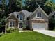 Charming two-story home featuring a stone facade, well-manicured lawn, and an attached two-car garage at 3045 Wyntree Dr, Peachtree Corners, GA 30071