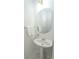 Compact powder room with a pedestal sink, decorative mirror, and clean white tile flooring at 3045 Wyntree Dr, Peachtree Corners, GA 30071