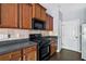 Functional kitchen with wood cabinets, black appliances, laminate countertops, and tile backsplash at 2872 Cross Creek Ct, Cumming, GA 30040