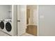 Well-lit laundry room features tile flooring, modern washer and dryer, and access to a bathroom at 6442 Canopy Dr, Sandy Springs, GA 30328