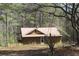 Charming exterior view of home with metal roof, wood siding and covered side porch surrounded by mature trees at 8740 Atlanta Newnan Rd, Chattahoochee Hills, GA 30268