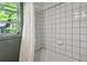 Minimalist white tiled bathroom features a window and a white shower curtain at 2029 Dover Hill Ne Pl, Atlanta, GA 30345