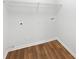 Bright laundry room featuring hardwood floors, utility connections, and shelving for functional organization at 4269 David Austin Ct, Snellville, GA 30039