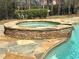 A stone trimmed in-ground pool with an attached spa features water streaming into the main pool at 621 Champions Dr, Mcdonough, GA 30253