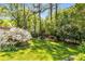 Spacious backyard features lush lawn, mature trees, flowering bushes, and a charming pergola with a built-in fire pit at 1919 Edinburgh Ne Ter, Atlanta, GA 30307