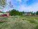 Spacious backyard with large grassy area, red shed, and house in the background, perfect for outdoor activities at 1076 Pinyan Ln, Canton, GA 30115