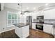 Modern kitchen with stainless steel appliances, central island, white cabinets, and stylish fixtures at 3911 Delfaire Trce, Cumming, GA 30040