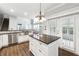Kitchen view featuring island, stainless steel appliances, tile backsplash, and wood floors at 3911 Delfaire Trce, Cumming, GA 30040