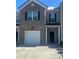 Two-story townhome featuring a one-car garage and a classic brick facade with black shutters at 6905 Rogers Pt, Lithonia, GA 30058