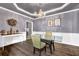 Formal dining room with a modern chandelier, wainscoting, and a glass-top table at 92 Creek Front Way, Lawrenceville, GA 30043