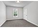 A simple carpeted bedroom featuring a large window, white door and neutral paint at 7474 Waterview Cv, Douglasville, GA 30135