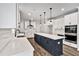 Bright kitchen boasts an island, white cabinets, stainless appliances, and modern pendant lights at 7474 Waterview Cv, Douglasville, GA 30135