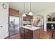 A kitchen view showing wooden cabinetry, granite countertops, stainless steel refrigerator, and seamless view to living areas at 3877 Valley Bluff Ln, Snellville, GA 30039