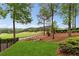 Golf course view, wrought iron fencing, mature trees, and landscaped backyard with charming wooden bridge at 5106 Davis Love Dr, Cumming, GA 30041