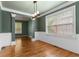 Green dining room with hardwood floors, white wainscoting, a modern light fixture, and large windows at 5106 Davis Love Dr, Cumming, GA 30041