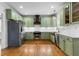 Updated kitchen features green cabinets, a stainless steel fridge, gas range, and subway tile backsplash at 5106 Davis Love Dr, Cumming, GA 30041