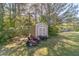 Storage shed and lawn equipment in a backyard with mature trees and a grassy lawn at 1542 Armende Cir, Dacula, GA 30019