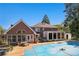 Brick home featuring a covered pool, patio with furniture, sunroom, and an outbuilding in a leafy backyard at 2405 Old Salem Se Rd, Conyers, GA 30013