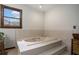 A bathtub with tiled surround, a window for natural light, and a cabinet for storage at 2405 Old Salem Se Rd, Conyers, GA 30013