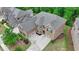 Aerial view of a brick home showing a three-car garage, well-manicured lawn, and beautiful landscaping at 4395 Wildbrooke Pkwy, Cumming, GA 30041