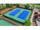 Aerial view of two tennis courts with blue courts and green surroundings, complemented by colorful landscaping at 4395 Wildbrooke Pkwy, Cumming, GA 30041