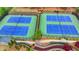 Aerial view of two tennis courts with blue courts and green surroundings, complemented by colorful landscaping at 4395 Wildbrooke Pkwy, Cumming, GA 30041