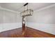 Dining room features hardwood floors, crown molding, modern chandelier, and a view into the kitchen area at 4631 Crooked Creek Ln, Villa Rica, GA 30180