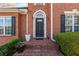 Close-up of a brick home entrance with a dark front door, classic black sconces, and landscaped planters at 4631 Crooked Creek Ln, Villa Rica, GA 30180