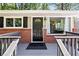Close-up of a charming home's entrance featuring a dark door, brick facade, and welcoming front porch at 1211 Argonne Ne Way, Atlanta, GA 30324