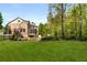 A wide expanse of verdant lawn, framed by a brick house and forest at 3215 Oxleas Ct, Cumming, GA 30041