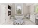 Bright bathroom features a soaking tub below a stained-glass window, double vanity, and marble floors at 3215 Oxleas Ct, Cumming, GA 30041