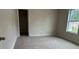 Neutral carpeted bedroom featuring a bright window, with the door ajar, offering a spacious and airy feel at 3536 Dogwood Pass, Stonecrest, GA 30038