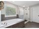 Bright main bathroom featuring soaking tub, tiled walk-in shower, and window at 85 Lawson St, Buford, GA 30518
