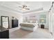 Bright main bedroom with tray ceiling, ceiling fan, black dressers and black framed full-length mirror at 85 Lawson St, Buford, GA 30518