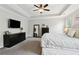 Bright main bedroom with tray ceiling, ceiling fan, black dressers and mounted television at 85 Lawson St, Buford, GA 30518