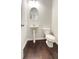 This half bathroom has wooden floors, a toilet, and a pedestal sink at 2102 Talmai Dr, Snellville, GA 30078