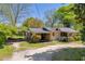 Single story home featuring a covered carport, screened-in porch, and mature trees on a sunny day at 215 Fair St, Loganville, GA 30052