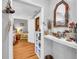 Hallway with hardwood floors and view into bedroom with a cozy chair and floral bedding at 215 Fair St, Loganville, GA 30052