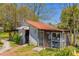 Rustic, weathered shed with vintage charm and a red metal roof surrounded by greenery at 215 Fair St, Loganville, GA 30052