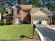 Charming two-story brick home featuring an attached two-car garage and well-maintained front lawn at 5001 Panola Mill Dr, Lithonia, GA 30038